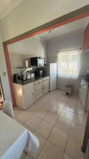 A compact kitchen with basic appliances, a window with curtains, and a tiled floor. - Comfortable getaway near Braga • 2 bedrooms - Up to 5 people (Crespos)