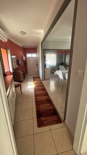 A narrow hallway with a wooden floor runner, a kitchen area with a dining table and chairs, and a door leading to another room. - Comfortable getaway near Braga • 2 bedrooms - Up to 5 people (Crespos)
