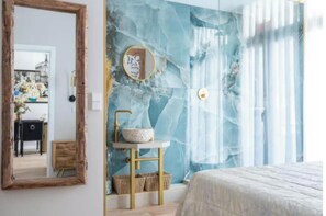 A bedroom with a marble wall, a round mirror, a bedside table with a bowl, and a bed. - Your Peaceful Luxury Stay in the Heart of Madrid (Madrid)