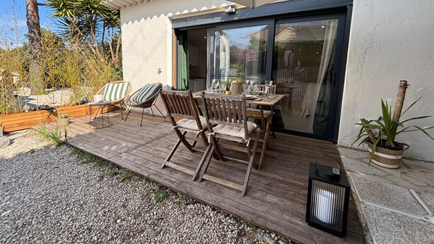 An outdoor patio with a wooden table and chairs, a potted plant, and a grill. - Mazet Léa - Quiet terrace & pool (Le Rouret)