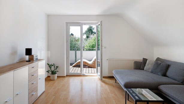 Una sala de estar moderna con un sofá, una mesa de centro y un ventanal corredizo que da a un espacio exterior.