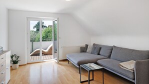 Una sala de estar moderna con un sofá gris, una mesita y una planta en maceta.