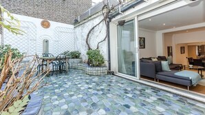 Un apartamento moderno con un patio empedrado, un sofá y una zona de comedor.