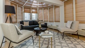 Una sala de estar moderna con sofá, sillón, mesa de centro y lámpara.