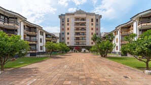 Un patio central con un edificio, rodeado de árboles y un sendero pavimentado.