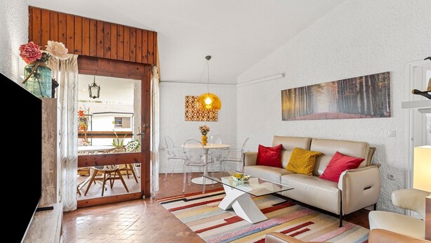 Una sala de estar con sofá, mesa de centro y comedor con sillas y mesa.