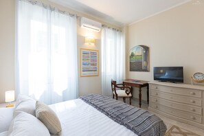 Un dormitorio con cama, escritorio, televisor y cómoda.