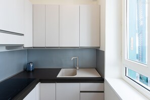 A modern kitchen with a built-in sink, a kettle, and a window with a view of buildings. - Alberico II Apartment (Rome)