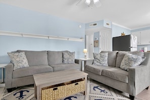 A living room with two grey sofas, a small wooden coffee table, and a patterned rug. - Unit A/B/C Walk to Beach/Intercoastal/Fishing Pier (Holly Ridge)