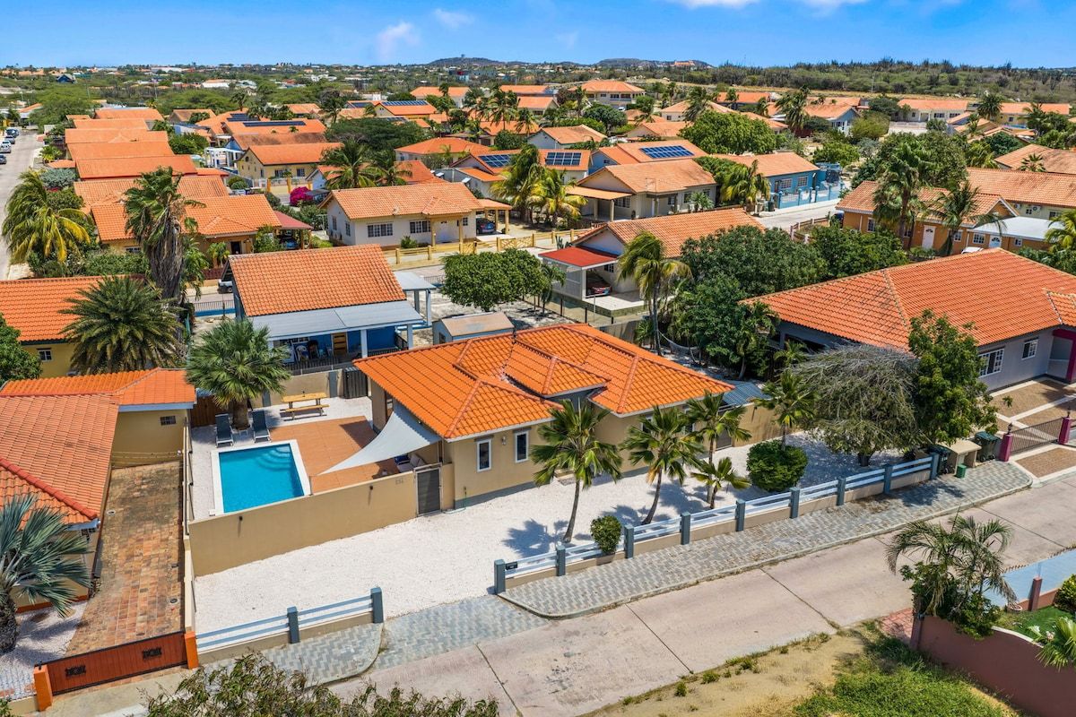 A residential area with houses, a swimming pool, and palm trees.