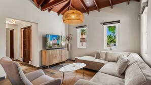 Ein Wohnzimmer mit hohen Decken, einer Couch, einem Couchtisch und einem Fernseher.