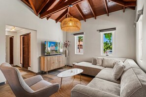 Un salon avec un plafond haut, un canapé, une table basse et un téléviseur.