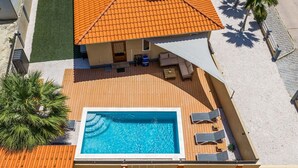 Ein Wohnhaus mit Swimmingpool, Sitzgelegenheiten im Freien und einem Ziegeldach.