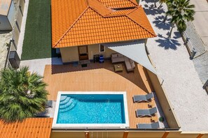 Une propriété résidentielle dotée d’une piscine, d’un espace extérieur aménagé et d’un toit recouvert de tuiles.