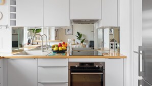Una cucina moderna con mobili bianchi, piano cottura in acciaio inossidabile e forno integrato.
