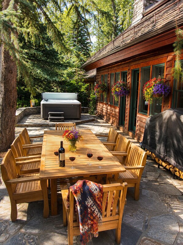 A wooden deck with a dining table and chairs, a barbecue grill, and a hot tub.