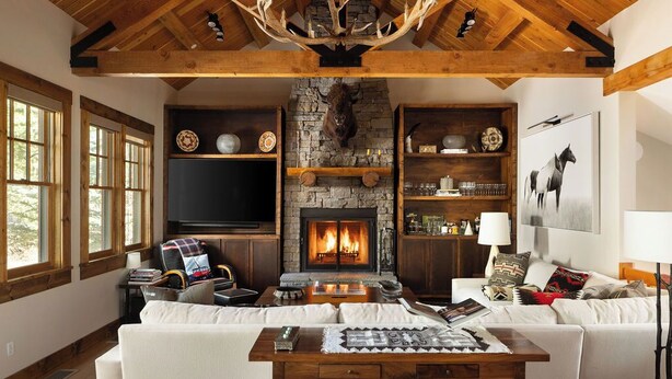 Un interior rústico con chimenea de piedra, vigas de madera, un televisor y un sofá.