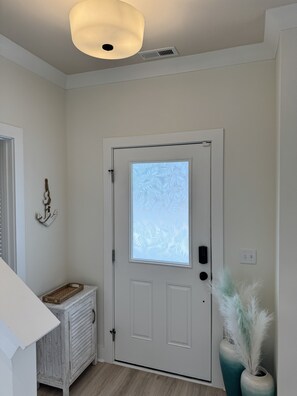 Une porte blanche avec un vitrage dépoli, un radiateur blanc, un luminaire fixé au mur et un interrupteur fixé au mur.