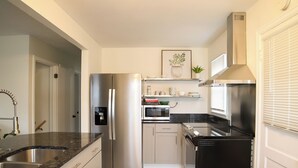 Una cocina moderna con electrodomésticos de acero inoxidable, encimera de mármol y horno empotrado.