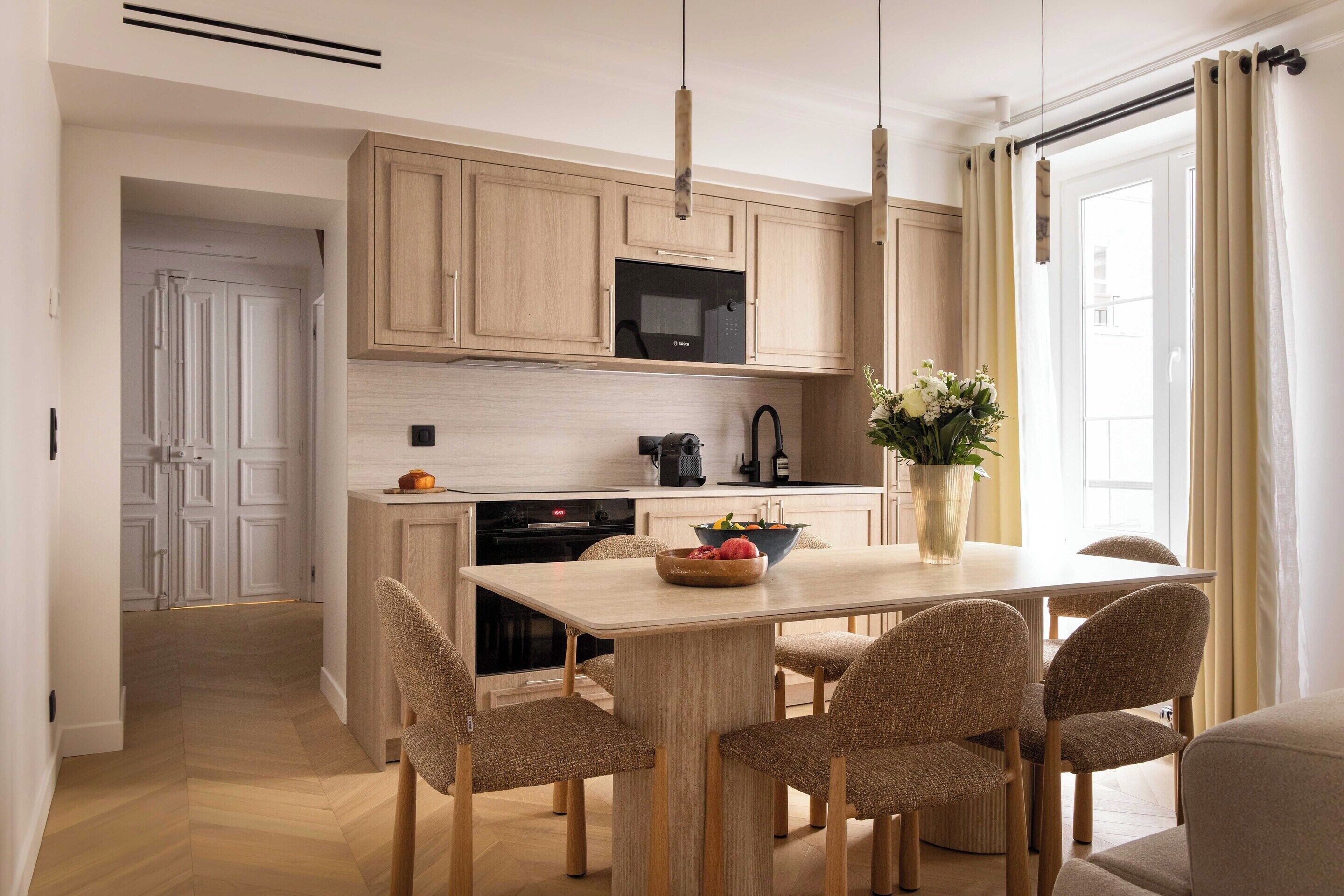 Una cocina moderna con armarios de madera, microondas y un comedor con mesa y sillas.
