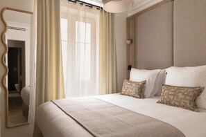 Ein Hotelzimmer mit einem großen Bett, einem Spiegel und einem Fenster mit Vorhängen.