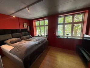 A bedroom with a bed, a window, and a television.