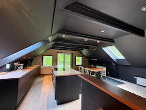 Una cocina moderna estilo loft con una isla central, electrodomésticos integrados y ventanas amplias.