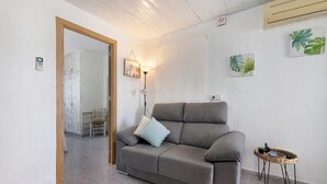 A living room with a grey sofa, a small side table, and a lamp. - Apartment 'Cristina' with Private Terrace, Wi-Fi, and Air Conditioning (Deltebre)