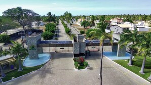 Ein Resort mit einem zentral gelegenen Pool, Palmen und einem gepflasterten Weg.