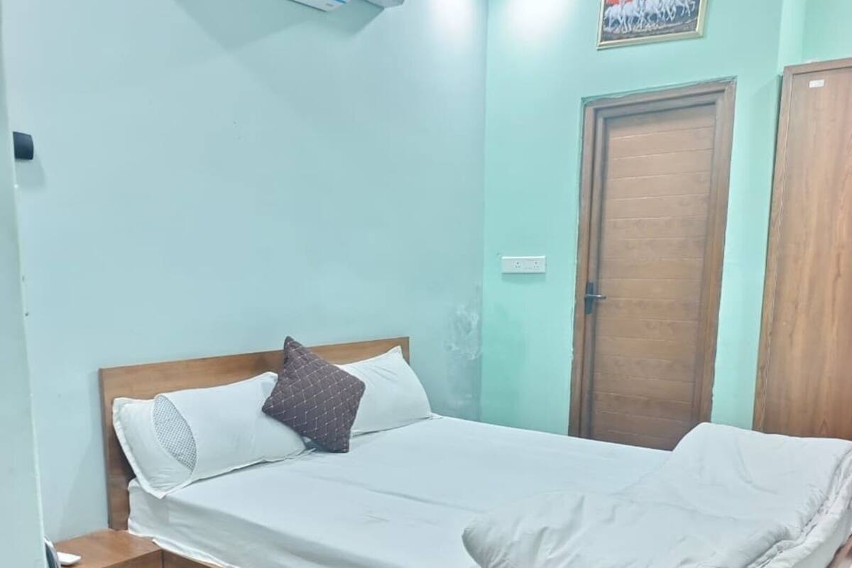A bedroom with a bed, a chair, a wardrobe, and an air conditioning unit.