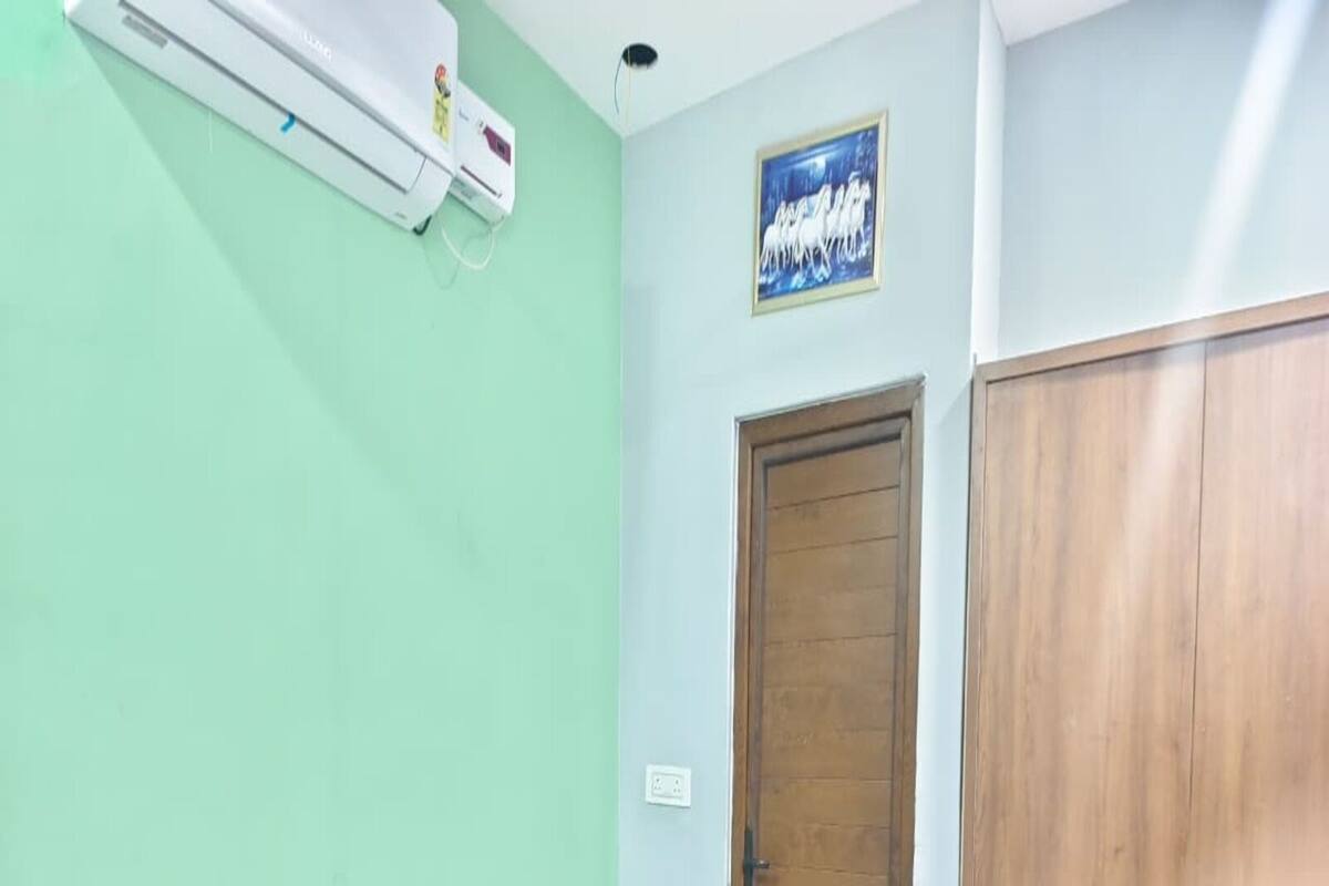 A bedroom with a bed, a wardrobe, a door, and an air conditioning unit.