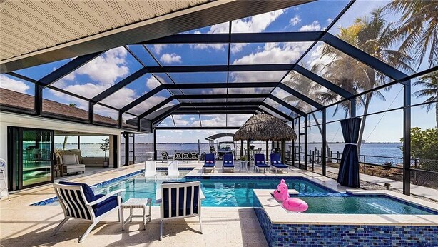 Une piscine couverte avec des chaises longues, une structure à toit de chaume et une vue sur la mer.