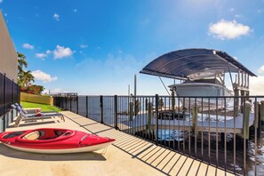 A covered boat dock with a kayak and lounge chairs on a concrete deck. - VRCC Villa Pura Vida (Cape Coral)