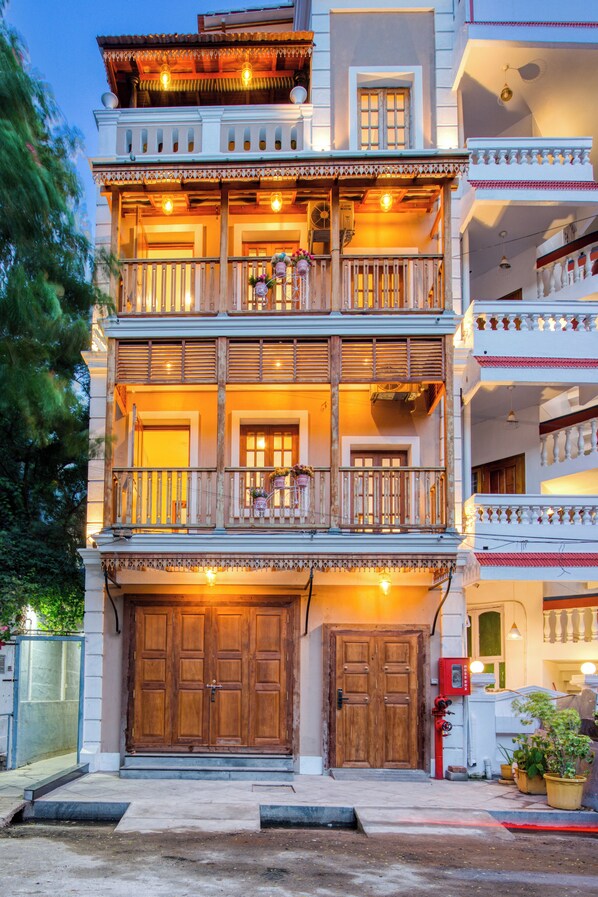 A multi-story building with balconies, wooden doors, and outdoor lighting.