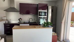 Una cocina moderna con armarios oscuros, un refrigerador de acero inoxidable y un horno empotrado.
