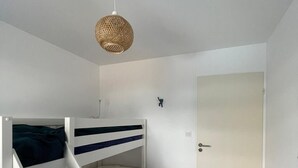 Una cama litera con escalera, puerta y lámpara colgante.