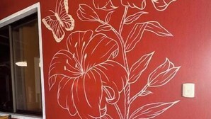 Una pared con un gran mural floral, una ventana y una puerta.
