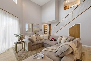 A modern living room with a sectional sofa, a small side table, and a staircase. - Hillside 2-Story | Dual Living | Mountain View (Vista)