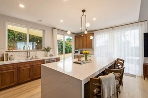 Una cocina moderna con una isla grande, armarios de madera y vistas al exterior.