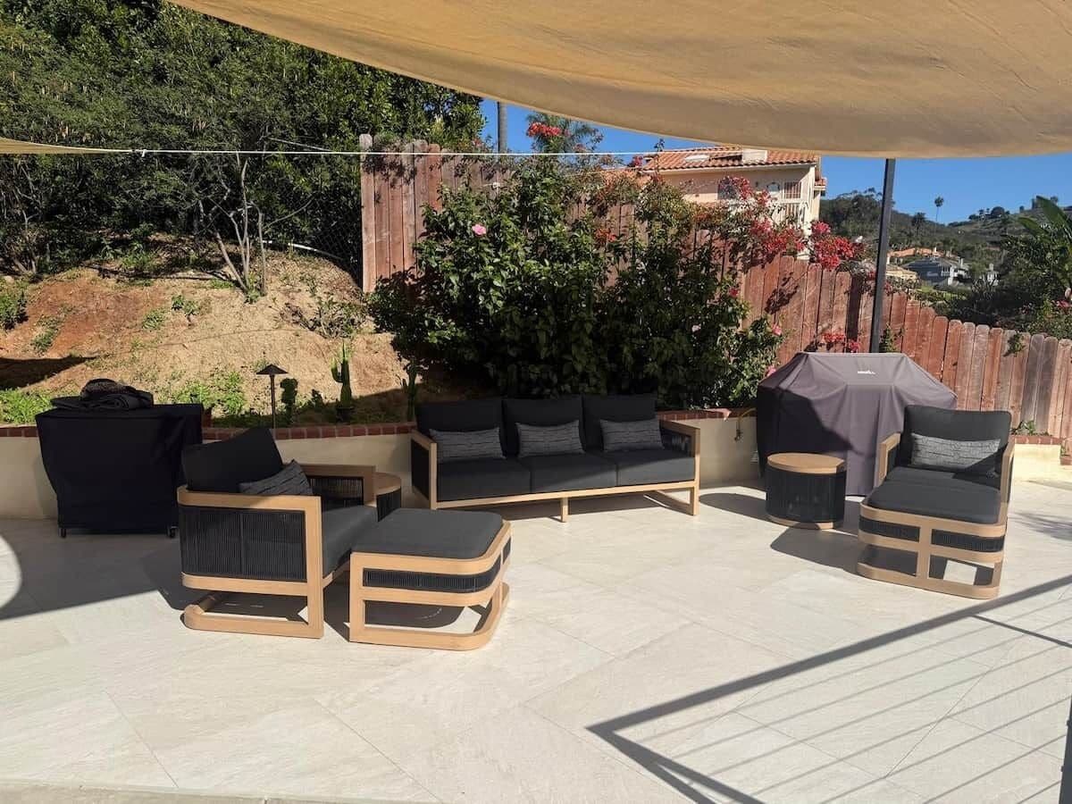 An outdoor patio area with a sofa set, a round table, and a covered grill.