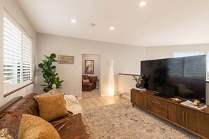 Ein modernes Wohnzimmer mit einer Ledersofa, einem Flachbildfernseher und einem Holzschrank.