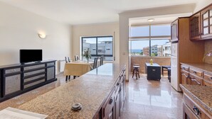 Una cocina moderna con encimeras de granito, un comedor con mesa y sillas, y vistas a través de un ventanal grande.