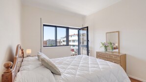 Un dormitorio con cama, cómoda y una ventana grande.