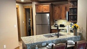 A kitchen with granite countertops, wooden cabinets, a stainless steel refrigerator, and a built-in sink. - Great Smokey Mountain Resort, condo Nestled between Gatlinburg & Pigeon Forge TN (Gatlinburg)