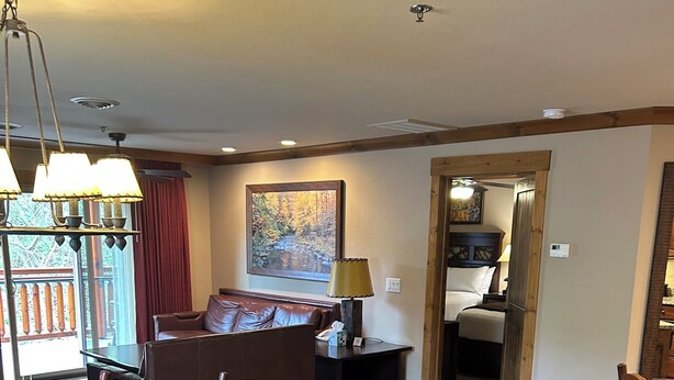 A dining area with a wooden table set for four, a sofa, and a lamp. - Great Smokey Mountain Resort, condo Nestled between Gatlinburg & Pigeon Forge TN (Gatlinburg)