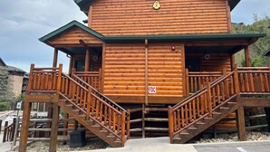A log cabin with a porch, a staircase, and a sign indicating it is a first-floor cabin. - Great Smokey Mountain Resort, condo Nestled between Gatlinburg & Pigeon Forge TN (Gatlinburg)