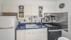 Una cocina con armarios blancos, un lavamanos, una estufa y un refrigerador.