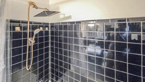 Ducha con cabezal de ducha manual y otro fijo en la pared, en un baño con azulejos.
