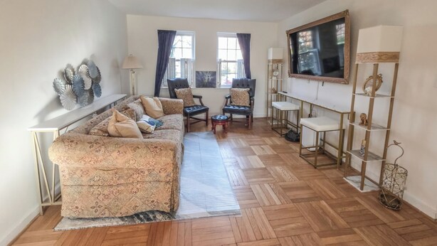 Una sala de estar con sofá, sillones, una mesa de centro, televisor y estantería.