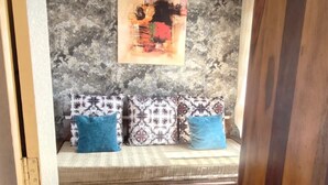 A room with a patterned sofa, a wall-mounted abstract painting, and a textured wall.
